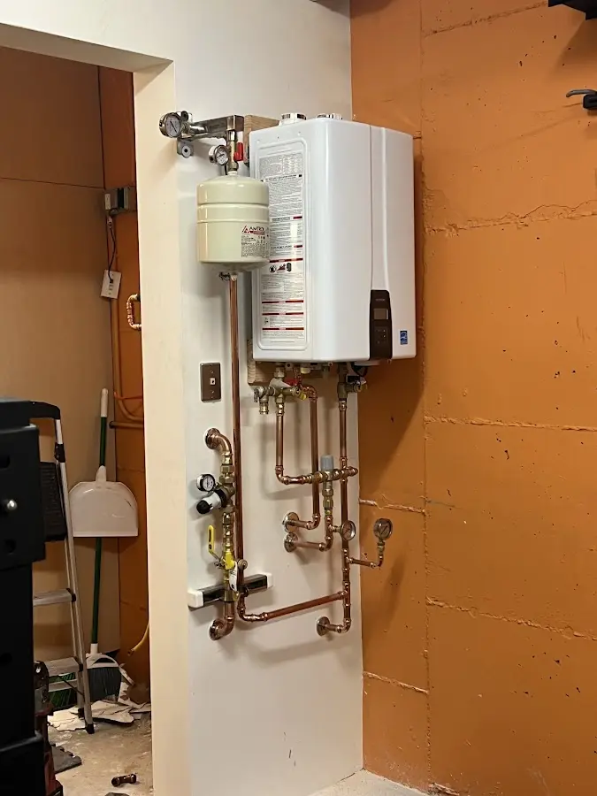 Plumbing technician inspecting water heater connections in Malone